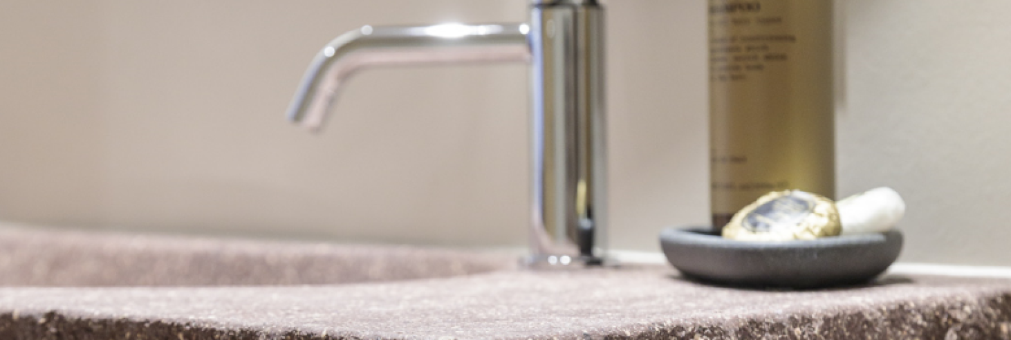 Waschbecken Porphyr Hotel Sole Waschbecken aus Südtiroler Porphyr im Boutique Hotel Sole in Sterzing, mit modernem Wasserhahn und Pflegeprodukten auf einer Ablage.