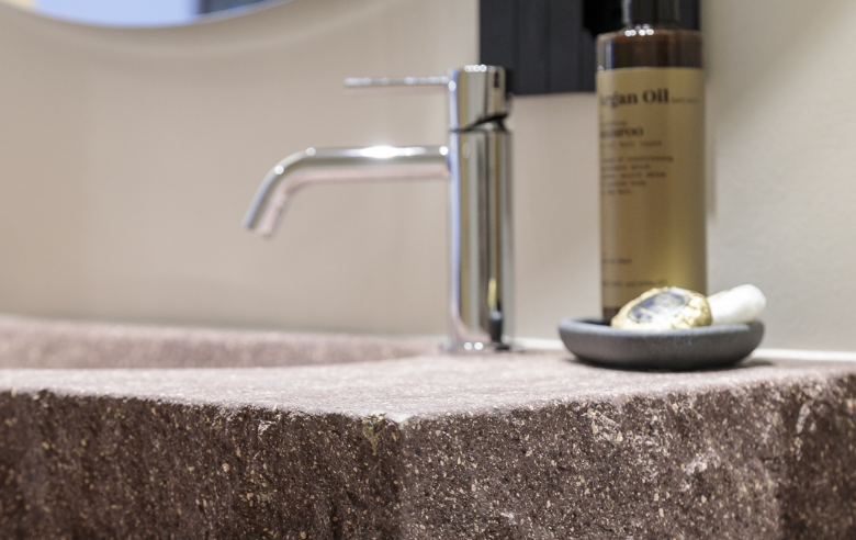 Waschbecken Porphyr Hotel Sole Waschbecken aus Südtiroler Porphyr im Boutique Hotel Sole in Sterzing, mit modernem Wasserhahn und Pflegeprodukten auf einer Ablage.