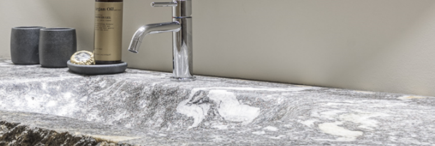 Badezimmer Apartment Gneis Edler Waschtisch aus Naturstein Gneis im Boutique Hotel Sole mit markanter Struktur, modernem Wasserhahn, runden Spiegeln und stilvollen Bad-Accessoires.