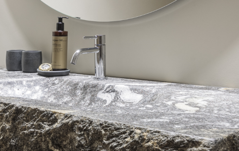 Badezimmer Apartment Gneis Edler Waschtisch aus Naturstein Gneis im Boutique Hotel Sole mit markanter Struktur, modernem Wasserhahn, runden Spiegeln und stilvollen Bad-Accessoires.