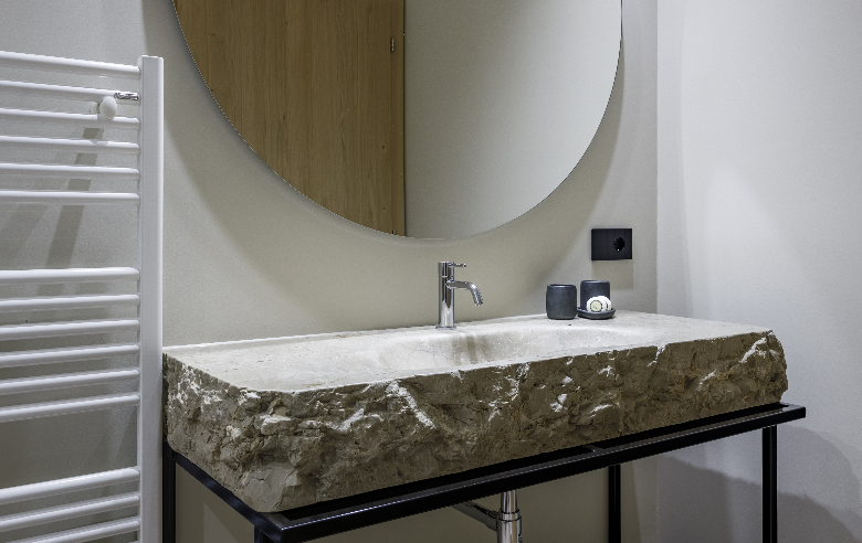 Badezimmer Dolomit Stylisches Badezimmer im Boutique Hotel Sole im Zentrum von Sterzing mit Naturstein-Waschbecken aus Dolomitgestein, modernem Wasserhahn und rundem Spiegel.