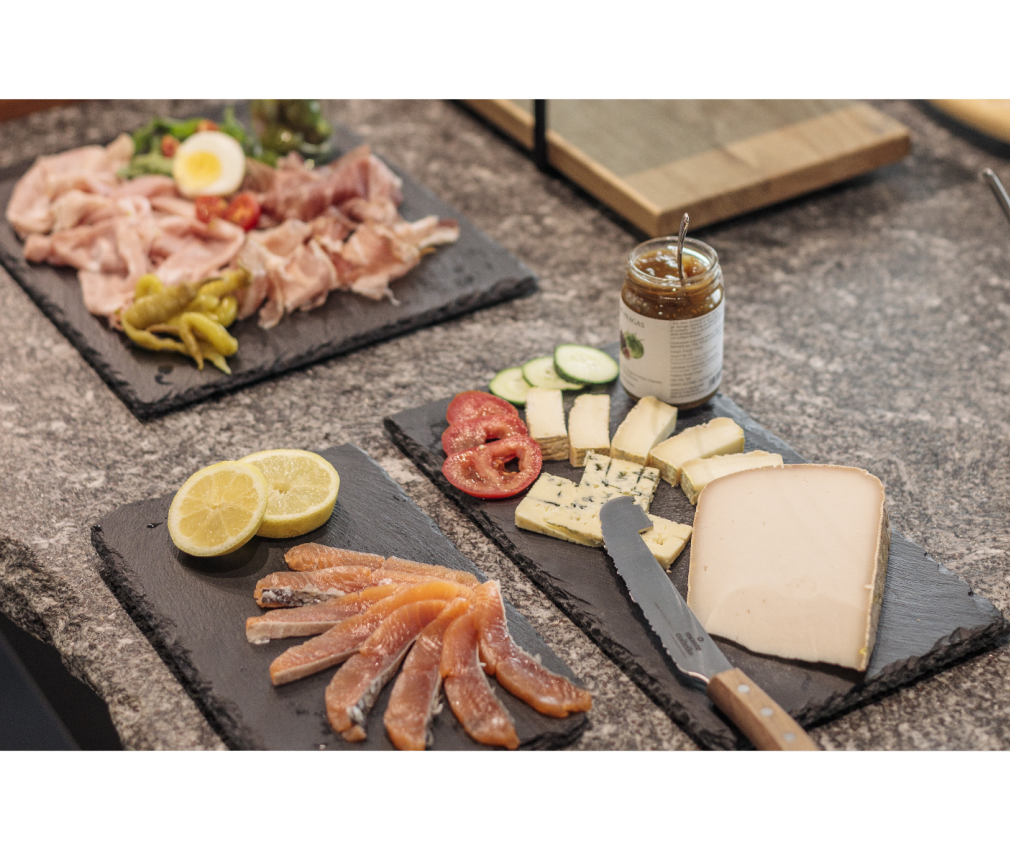 Aufschnitt im Hotel Sole Frühstück im Boutique Hotel Sole in Sterzing mit geräuchertem Lachs, Käse, Aufschnitt, frischem Gemüse und Marmelade auf schwarzen Schieferplatten.