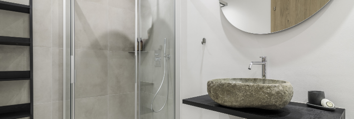 Badezimmer im Hotel Sole Modernes Badezimmer mit begehbarer Glasdusche, stilvollem Naturstein-Waschbecken und minimalistischer Einrichtung im Boutique Hotel Sole in Sterzing, Südtirol.