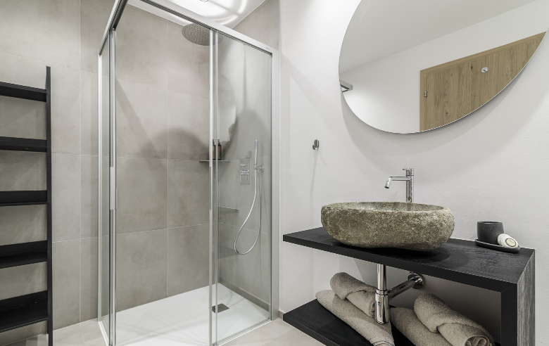 Badezimmer im Hotel Sole Modernes Badezimmer mit begehbarer Glasdusche, stilvollem Naturstein-Waschbecken und minimalistischer Einrichtung im Boutique Hotel Sole in Sterzing, Südtirol.