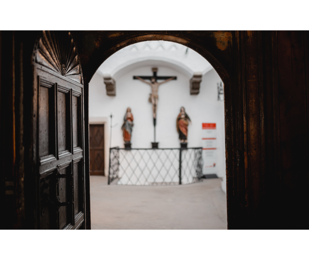 Rathaus Sterzing Eine alte Holztür, im Rathaus von Sterzing mit Kruzifix und Heiligenstatuen. Die historische Architektur betont die spirituelle Atmosphäre.