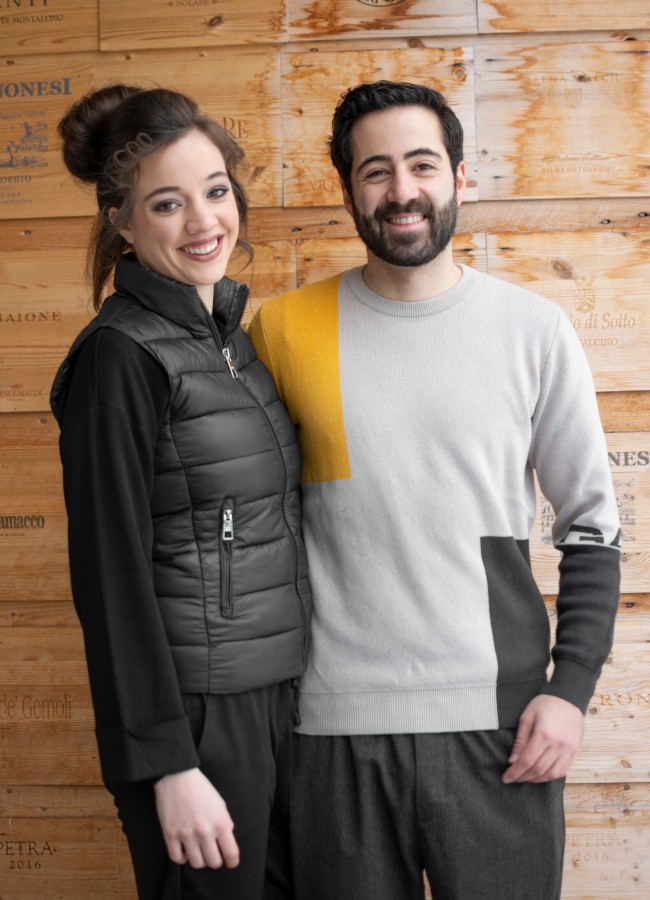 Die Gastgeber Die Gastgeber des Boutique Hotel Sole im Zentrum von Sterzing Johannes und Nadine vor einer Wand aus Holz in der Enothek Mair Mair in Südtirol