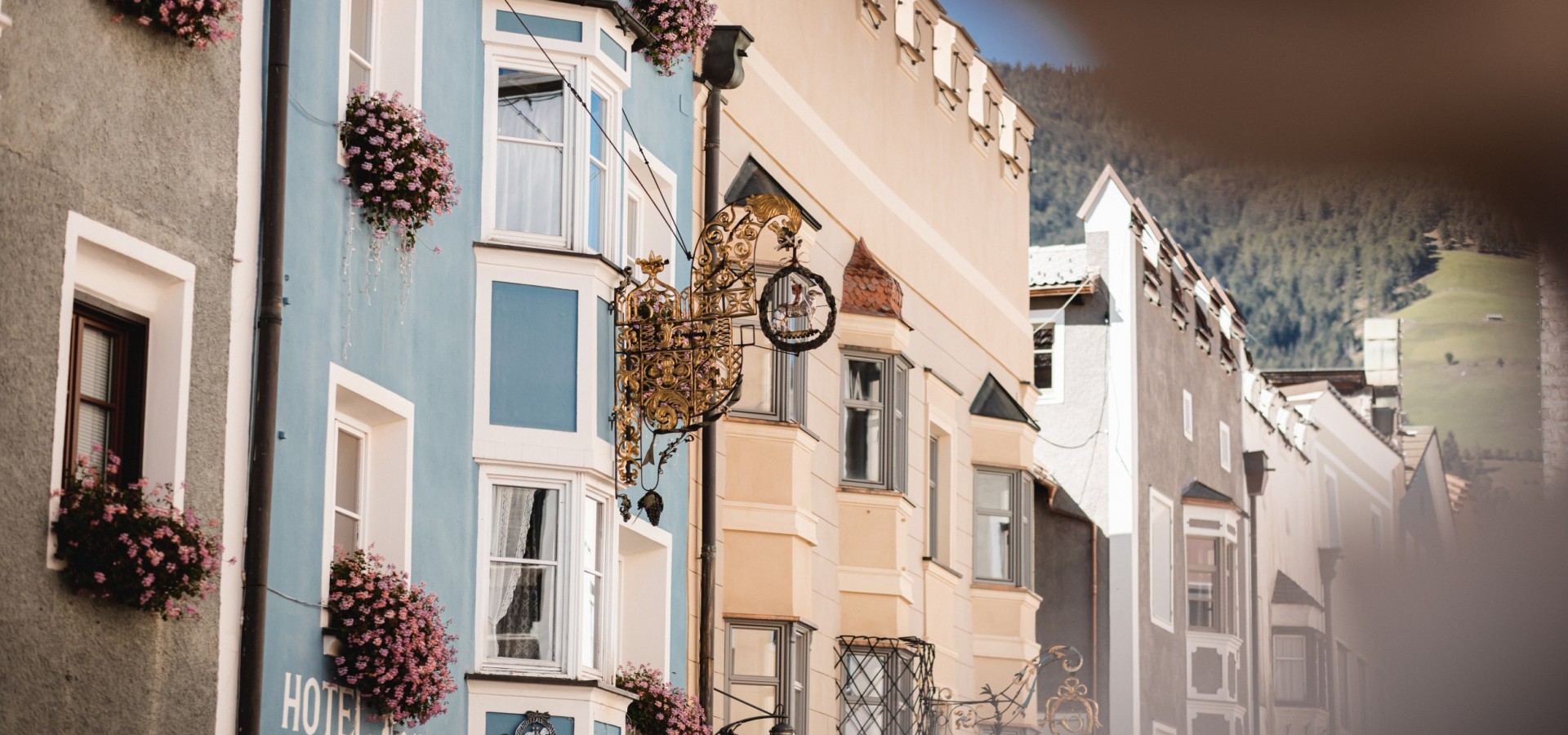Facciate storiche del centro storico con balconi fioriti, nel cuore di Vipiteno, Alto Adige. Architettura affascinante e le Alpi sullo sfondo. Centro città di Vipiteno.