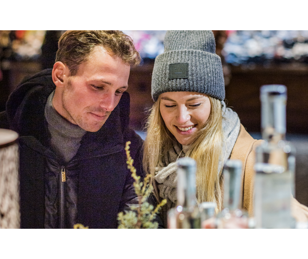 Weihnachtsmarkt Einkaufen Paar auf dem Weihnachtsmarkt in Sterzing betrachtet regionale Spezialitäten und bummeln über den Markt. Stimmungsvolle Beleuchtung.