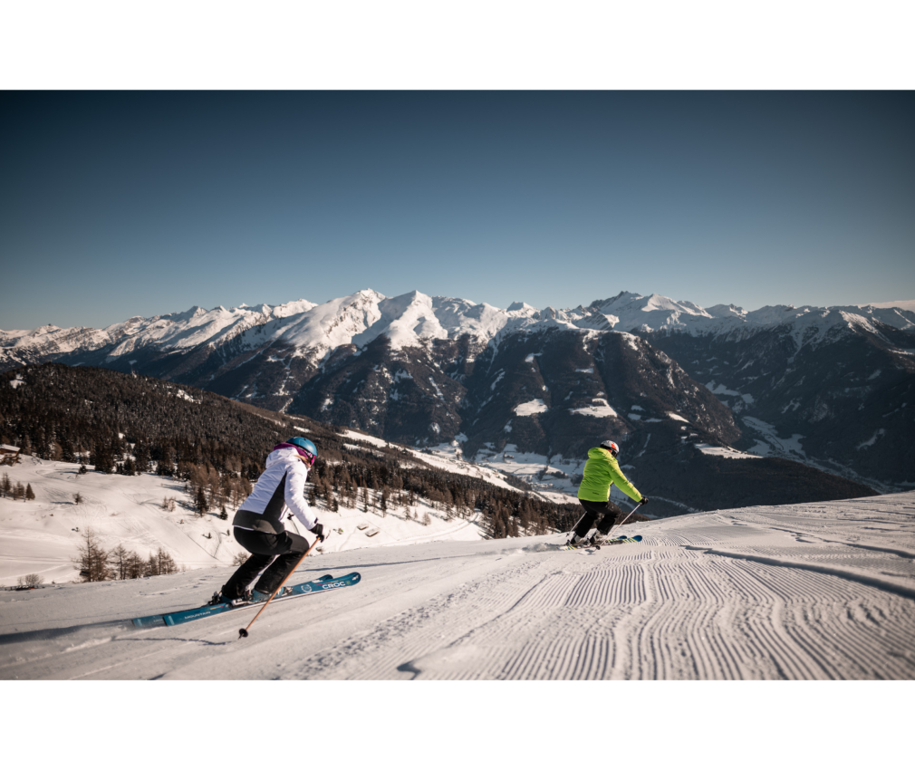 Skifahrer auf einer frisch präparierten Piste am Rosskopf in Südtirol mit atemberaubendem Bergpanorama auf das Pfitscher-Tal, Sterzing und Gossensass.