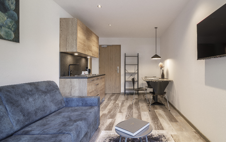 Dolomit Apartment Hotel Sole Modernes Apartment im Boutique Hotel Sole in Sterzing, Südtirol. Offene Küche, gemütliches Sofa, Esstisch aus Dolomitgestein mit Designerstühlen und Wand-TV.
