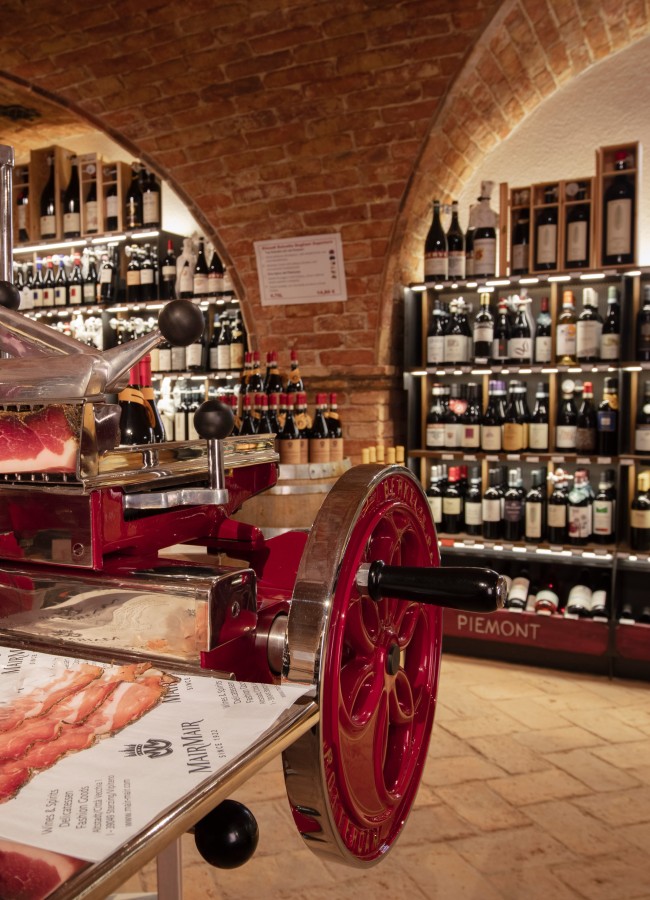 Berkel im Keller Mair Mair Traditionelle Berkel-Aufschnittmaschine mit hochwertigem Südtiroler Speck im historischen Weinkeller von Mair Mair mit edlen Weinen aus dem Piemont.