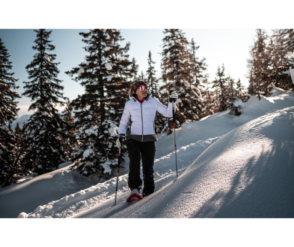 Frau beim Schneeschuhwandern in den verschneiten Alpen von Südtirol. Winterlandschaft mit tiefem Schnee, Sonnenschein und verschneiten Tannen.