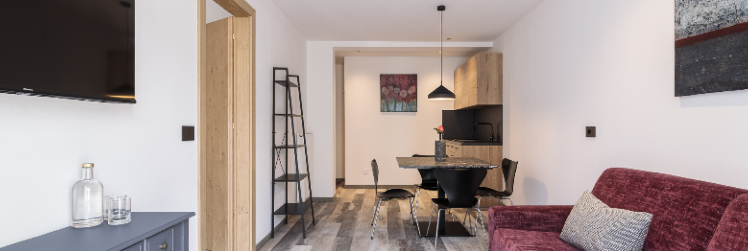 Apartment Gneis Hotel Sole Modern eingerichtetes Apartment Gneis im Boutique Hotel Sole mit offener Wohnküche, Esstisch, gemütlichem Sofa, TV und stilvollen Holzelementen.