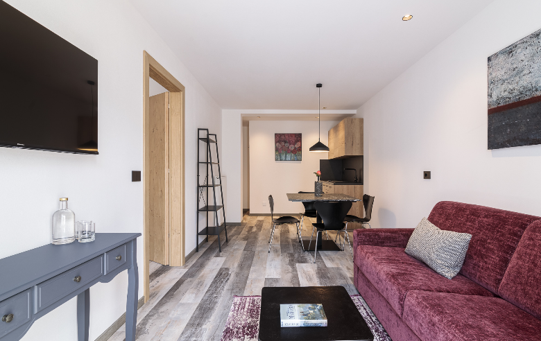 Apartment Gneis Hotel Sole Modern eingerichtetes Apartment Gneis im Boutique Hotel Sole mit offener Wohnküche, Esstisch, gemütlichem Sofa, TV und stilvollen Holzelementen.