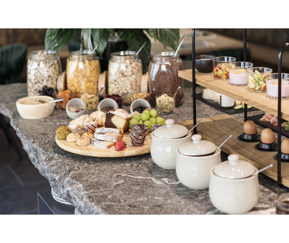 Frühstück im Boutique Hotel Sole in Sterzing Ein reichhaltiges Frühstücksbuffet im Boutique Hotel Sole in Sterzing mit Müsli, frischem Gebäck, Joghurt, Obst und Eiern auf einer Natursteinplatte angerichtet.
