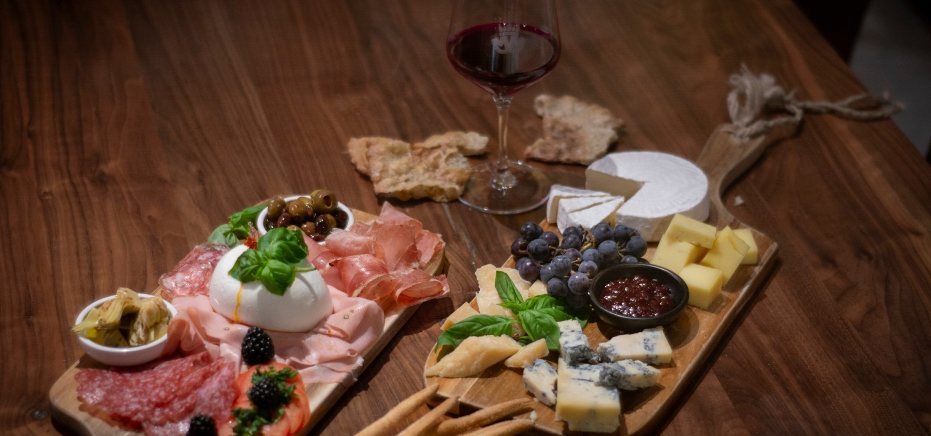 Feinkost Aperitivo bei Mair Mair Genussvolle Feinkost bei Mair Mair in Sterzing: Edle Käse- und Wurstspezialitäten, begleitet von knusprigem Brot, Oliven und Rotwein, serviert auf stilvollen Holzbrettern.