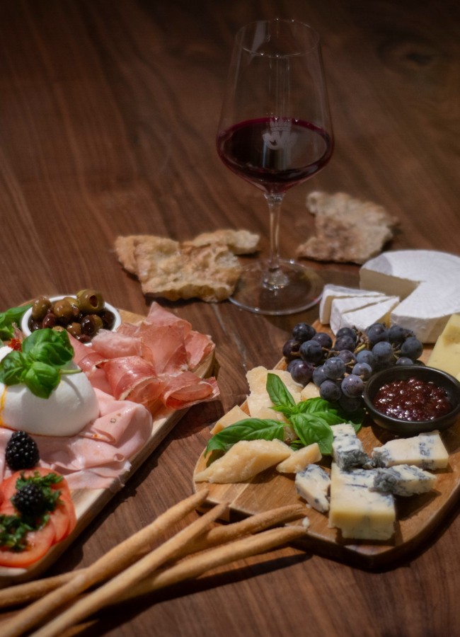 Antipasti im Mair Mair Edle Antipasti-Platten mit italienischem Käse, Wurst, Oliven, Burrata und Trauben, serviert mit einem Glas Rotwein in der Enothek Mair Mair in Sterzing