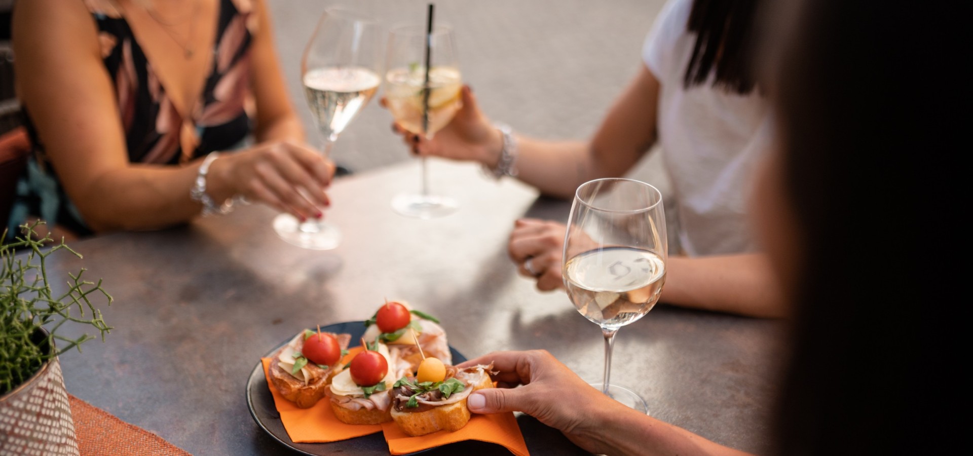 Drei Frauen genießen Aperitif und Canapés in einem Café im Zentrum von Sterzing in Südtirol. Aperitif mit Weißwein und Snacks in mediterraner Atmosphäre.