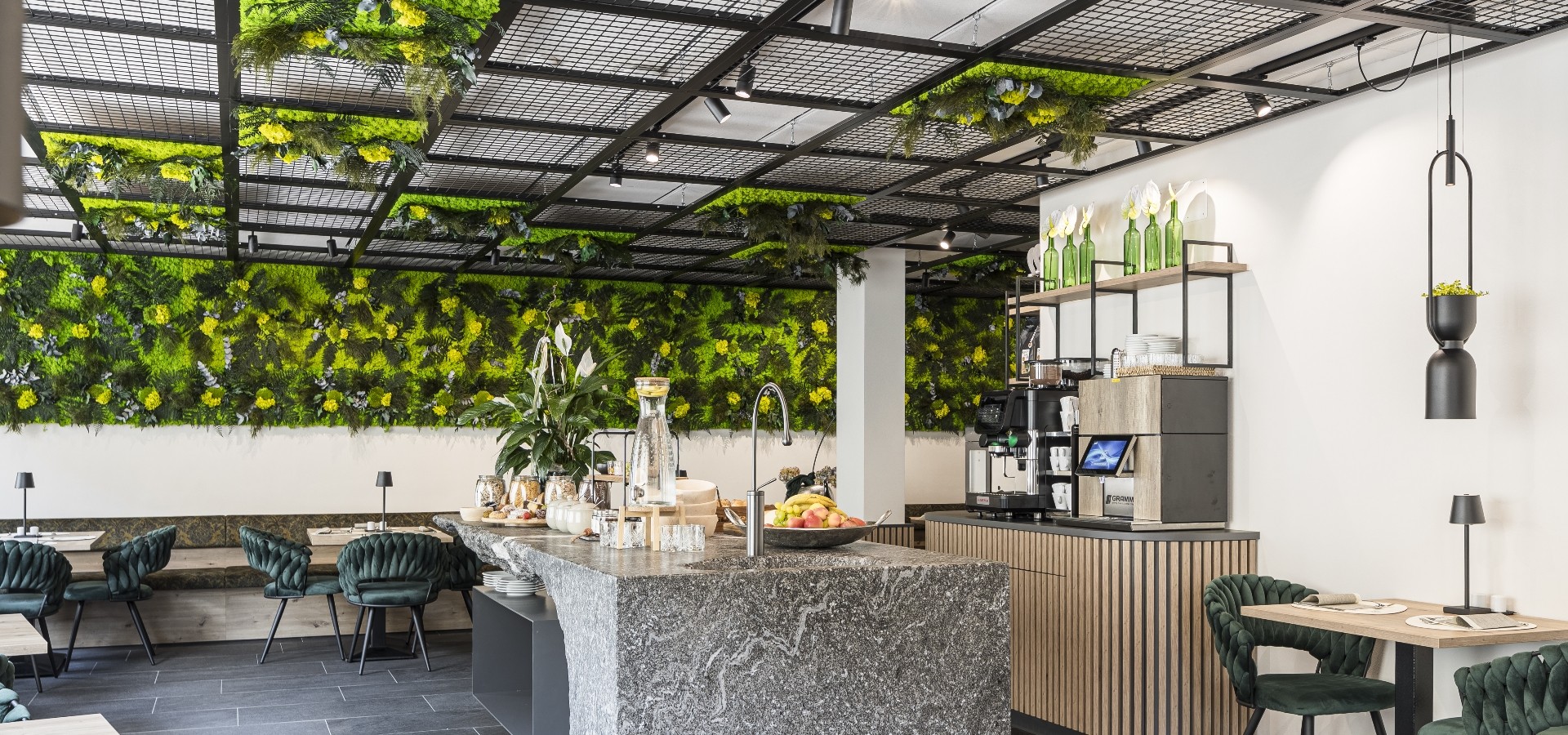 Frühstücksraum Hotel Sole mit Mooswand Frühstücksbereich im Boutique Hotel Sole mit einer Naturstein-Theke, einer grünen Pflanzenwand und stilvollen Sitzbereichen in einem Boutique-Hotel.