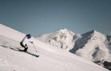 Skifahren am Rosskopf bei Sterzing Skifahrerin, die elegant eine verschneite Piste hinabfährt. Die schneebedeckten Wipptaler Alpen im Hintergrund nahe Sterzing in Südtirol