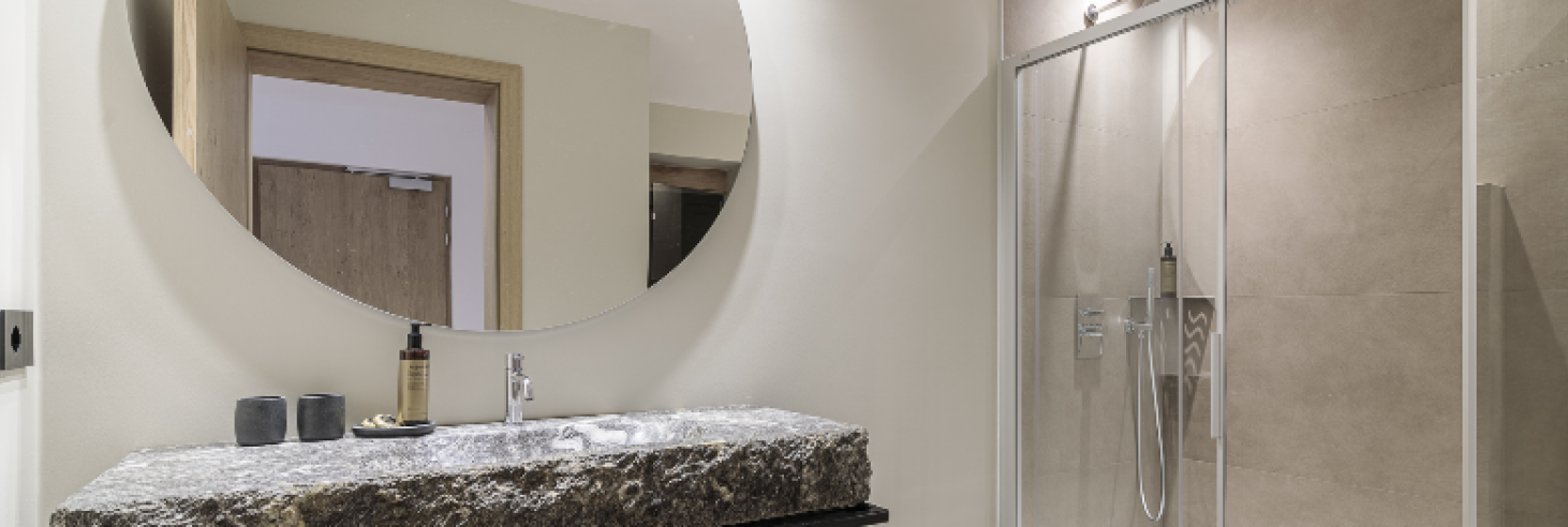 Badezimmer Gneis Apartment Badezimmer des Apartments Gneis im Boutique Hotel Sole mit markantem Gneis-Waschbecken, großer runder Spiegel, bodengleicher Dusche und stilvollen Details.