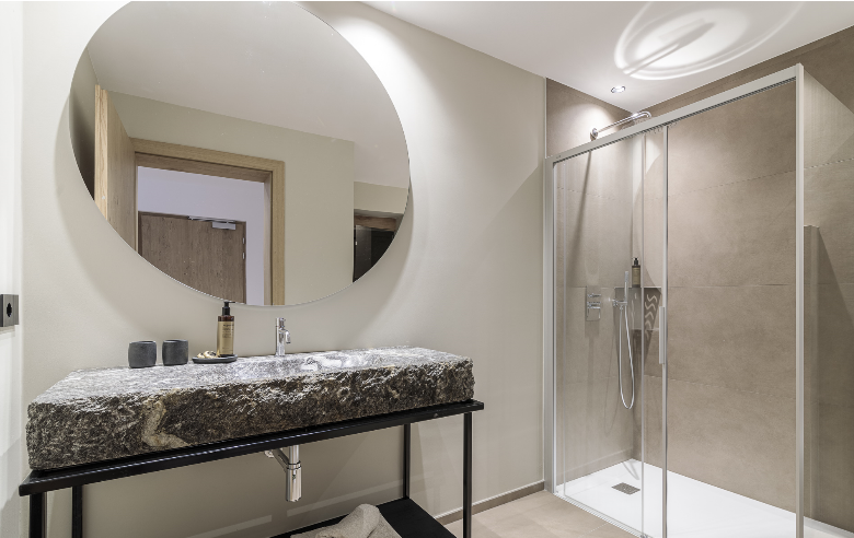 Badezimmer Gneis Apartment Badezimmer des Apartments Gneis im Boutique Hotel Sole mit markantem Gneis-Waschbecken, großer runder Spiegel, bodengleicher Dusche und stilvollen Details.