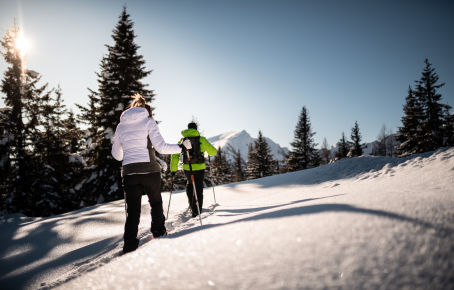 Rosskopf Skitour Zwei Personen beim Schneeschuhwandern in einer verschneiten Berglandschaft. Die Sonne scheint, der Schnee glitzert, und die Bergkulisse ist atemberaubend.