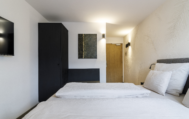 Zimmer im Boutique Hotel Sole Modern eingerichtetes Hotelzimmer mit einem großen, gemütlichen Bett, stilvollen dunklen Möbeln und stimmungsvollem Licht für eine entspannte Atmosphäre.
