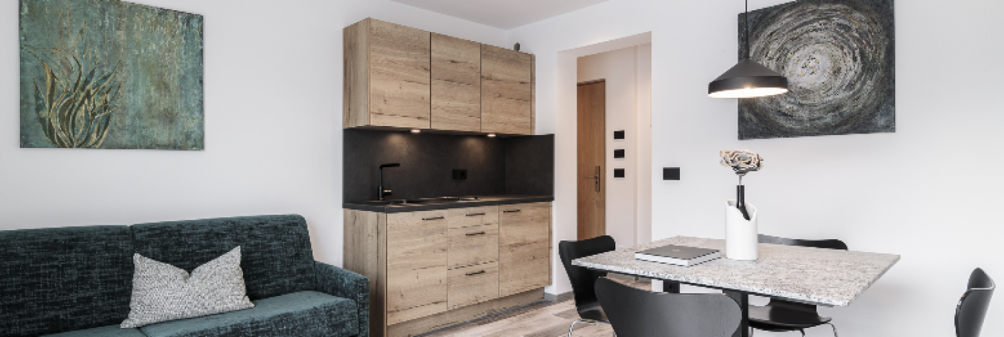 Wohnbereich Plima Moderner Wohnbereich im Boutique Hotel Sole mit offener Küche, Natursteintisch, grüner Couch und stilvoller Beleuchtung für ein elegantes Ambiente.