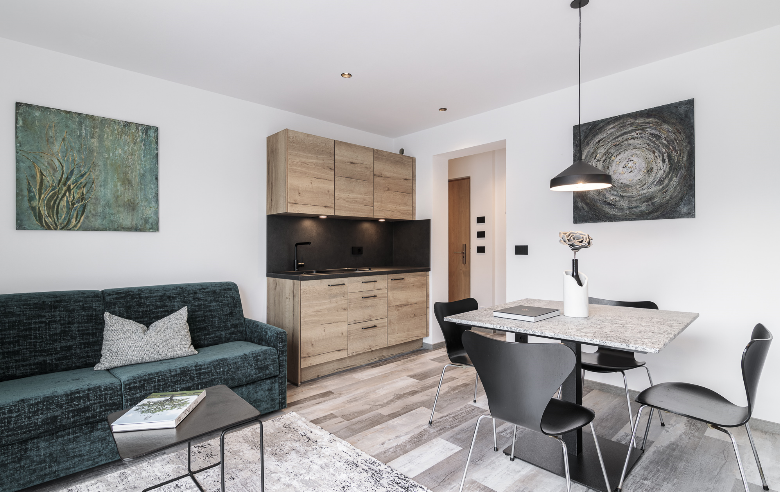 Wohnbereich Plima Moderner Wohnbereich im Boutique Hotel Sole mit offener Küche, Natursteintisch, grüner Couch und stilvoller Beleuchtung für ein elegantes Ambiente.