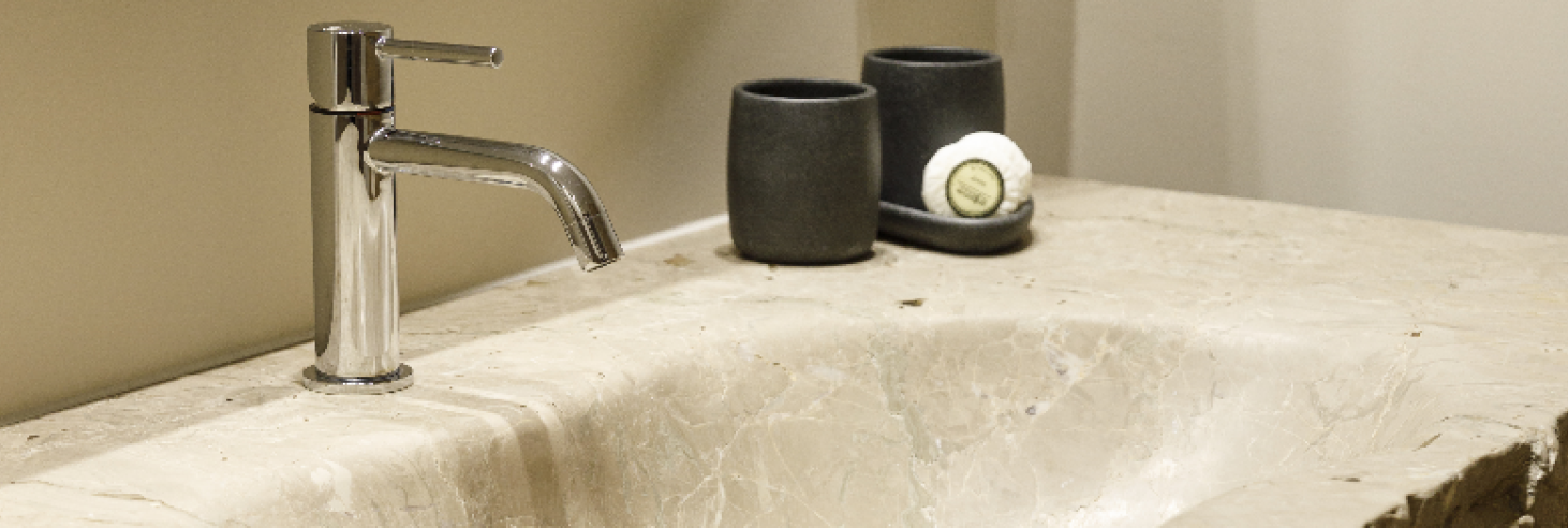 Dolomit Waschbecken Hotel Sole Elegantes Badezimmer im Boutique Hotel Sole in Sterzing, Südtirol. Naturstein-Waschbecken mit moderner Armatur, stilvolle schwarze Becher und Seife.