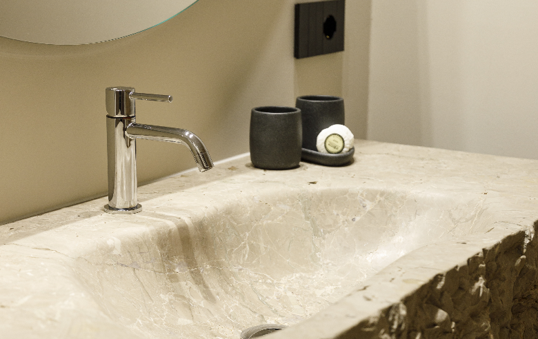 Dolomit Waschbecken Hotel Sole Elegantes Badezimmer im Boutique Hotel Sole in Sterzing, Südtirol. Naturstein-Waschbecken mit moderner Armatur, stilvolle schwarze Becher und Seife.