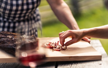 Brettel-Jause im freien Zwei Personen bei einer gemütlichen Brettel-Jause mit geschnittenem Südtiroler Speck, einem Glas Rotwein und den Sterzinger Umland im Hintergrund